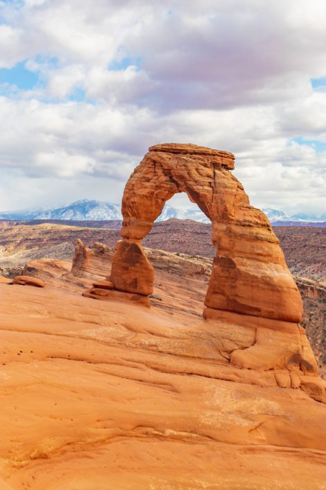 hikes in arches national park the delicate arch with the la sal mountains behind it. this trail is one of the most popular for hiking in arches national park.
