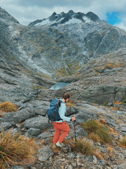 Using trekking poles on the steep descent of Gertrude Saddle in New Zealand, showing how trekking poles help with balance on technical terrain
