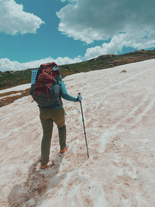 Backpacking and hiking on snow using trekking poles for balance and stability on uneven terrain in the mountains