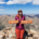 Emma standing on the summit of Mount Elbert holding wooden sign at 14,440 feet, highest 14er in Colorado Rockies