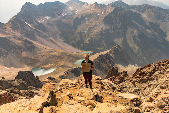 Emma hiking 14ers standing on the summit of Mount Sneffels, a Class 3 Colorado 14er in the San Juan Mountains