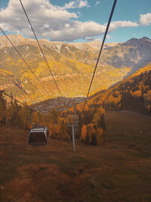 View from the Telluride gondola looking down at the town with golden aspens during fall in Colorado