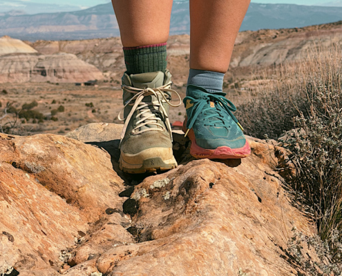 trail runners vs hiking boots comparison showing one of each worn on rocky terrain