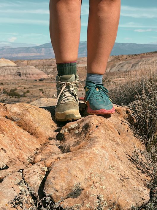 trail runners vs hiking boots comparison showing one of each worn on rocky terrain