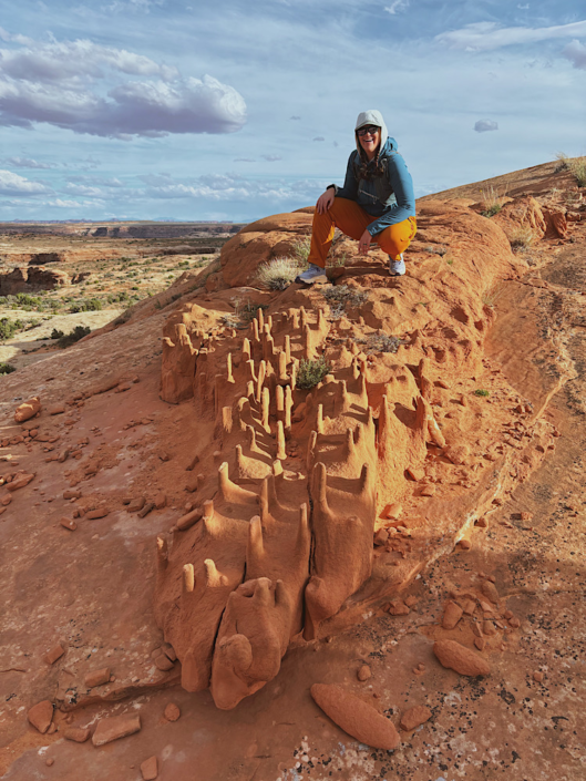 Crouching on Crocodile Rock formation near Colonnade Arch in Utah desert landscape