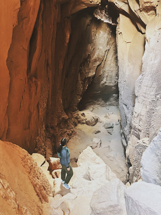 Scrambling down boulders into Goblin’s Lair in Goblin Valley State Park Utah