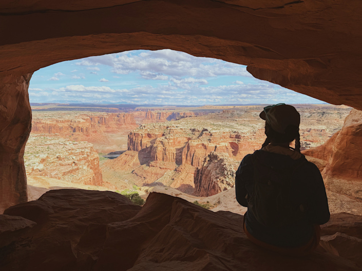 Sitting under the largest arch at Colonnade Arch looking out over canyon views in Utah
