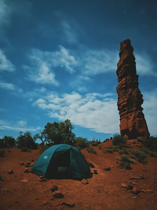 Tent under the stars at Standing Rock campsite in the Maze in Canyonlands with rock formations silhouetted at night