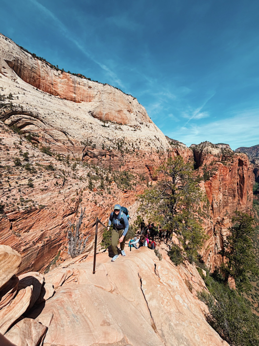 Hiker carefully climbing the chain section during the Angels Landing hike in Zion National Park