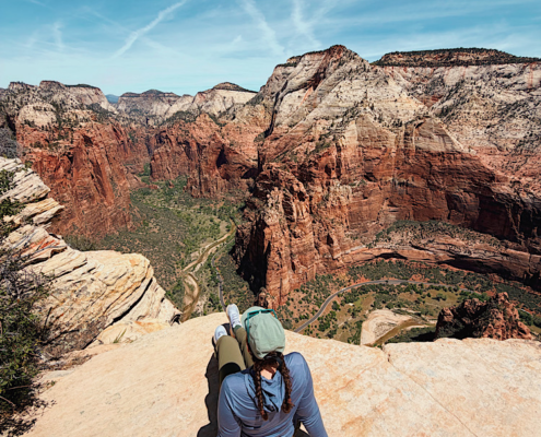 Emma sitting on cliff at the summit of the Angels Landing hike in Zion National Park overlooking Zion Canyon