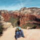 Emma sitting on cliff at the summit of the Angels Landing hike in Zion National Park overlooking Zion Canyon
