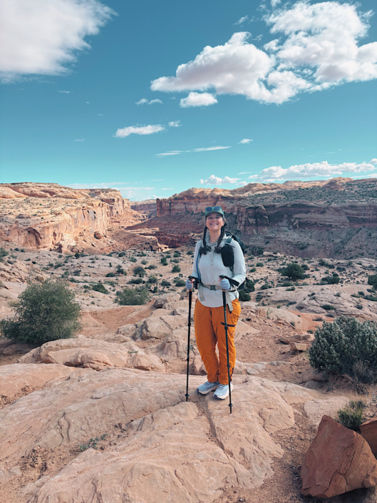 Emma standing at the rim of Horseshoe Canyon with sandstone cliffs and blue sky in Canyonlands National Park