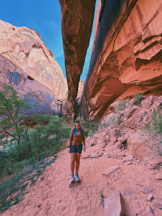 Hiker standing beneath Morning Glory Natural Bridge at the end of the Grandstaff Canyon Trail