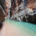 Blue water flowing through The Narrows hike in Zion National Park with towering sandstone slot canyon walls rising above the river.