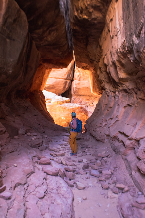 Hiker walking through a narrow sandstone passage on the Chesler Park Loop in the Needles District.