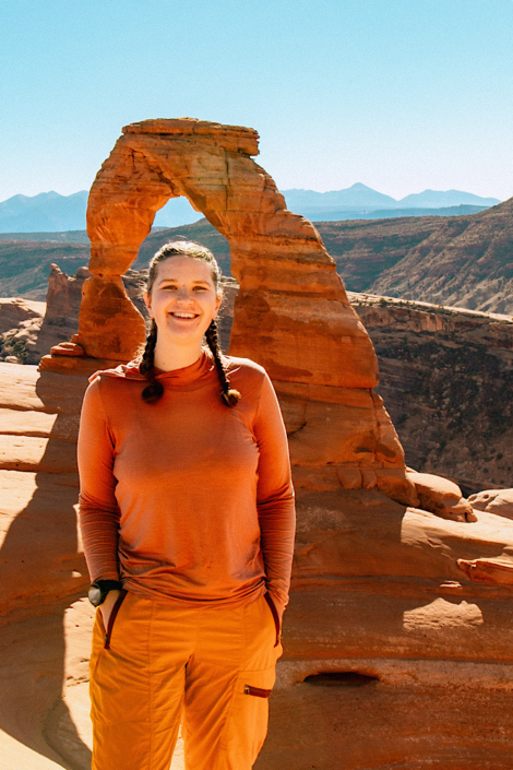 Hiker standing in front of Delicate Arch in Arches National Park.