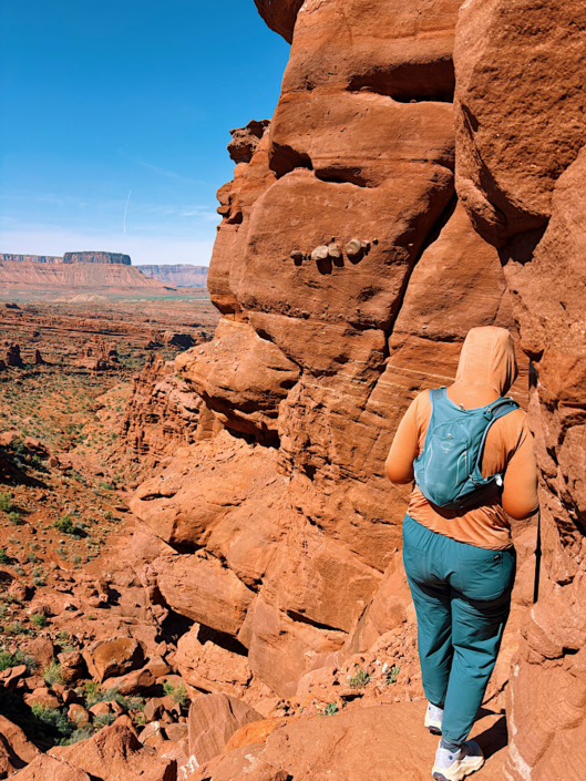 Hiking along a narrow section of the Fisher Towers Trail with steep canyon views