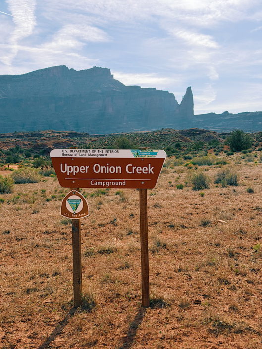 Upper Onion Creek Campground sign with Fisher Towers rising in the background near Moab