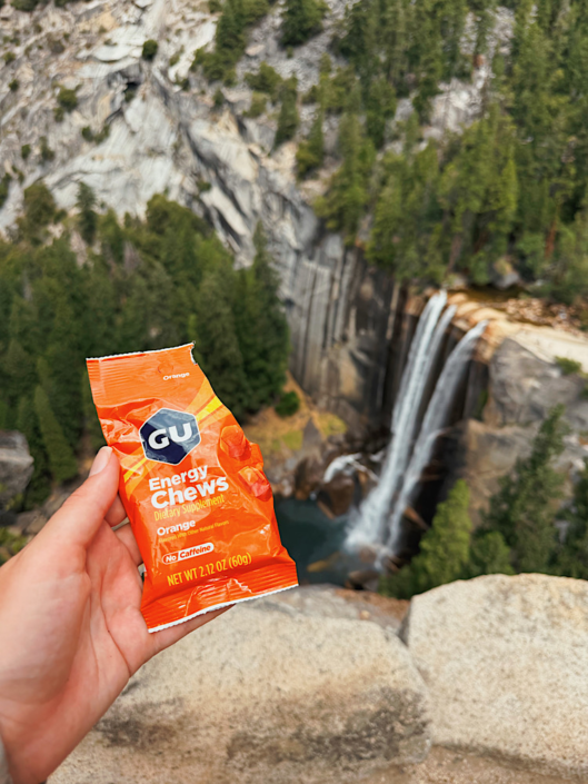 Hiker holding GU chews in front of a waterfall