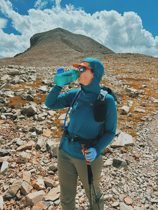 Hiker drinking electrolyte water from a Nalgene bottle on a hike