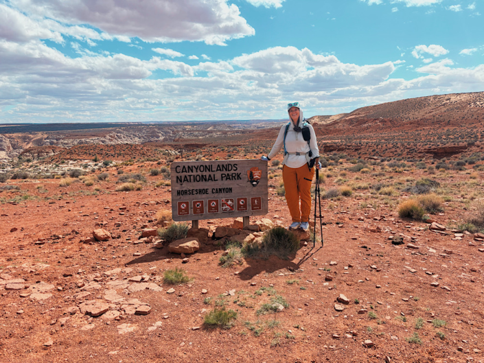 Hiker standing beside the Horseshoe Canyon sign in Canyonlands National Park