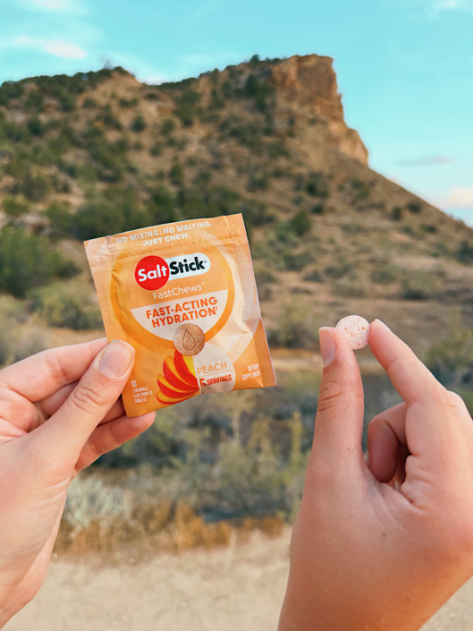 Emma holding a SaltStick electrolyte packet and tablet for hiking