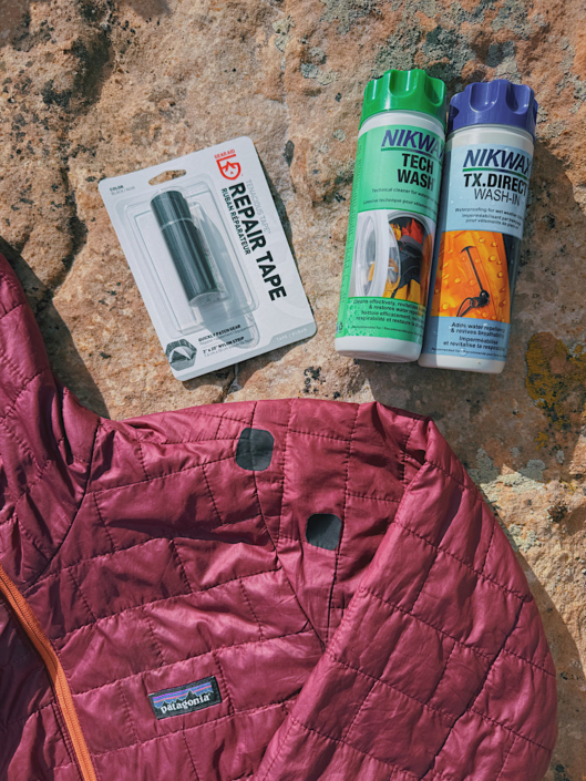 Gear Aid repair tape and Nikwax gear wash next to a repaired Patagonia puffy jacket
