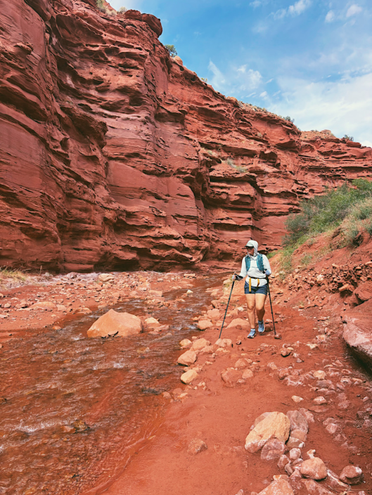 Hiker walking next to Professor Creek water in Mary Jane Slot Canyon near Moab, Utah