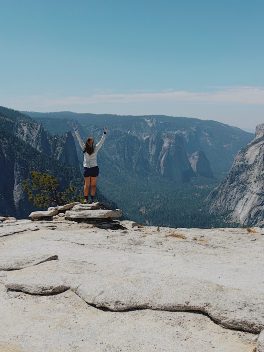 Hiker standing at the end of North Dome looking down Yosemite Valley