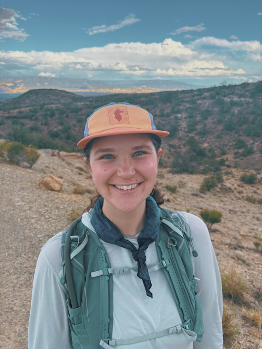 Hiker wearing a sun shirt, hat, and cooling neck gaiter while hiking in the desert