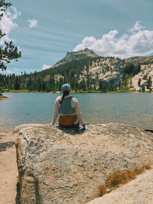Hiker sitting on a rock overlooking Upper Cathedral Lake in Yosemite