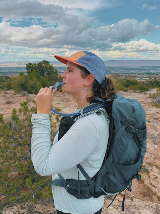 Hiker drinking water from a hydration bladder while hiking in the desert