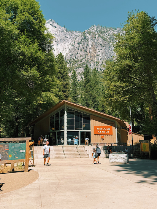 Yosemite Welcome Center building surrounded by tall pine trees and granite cliffs in Yosemite Valley.